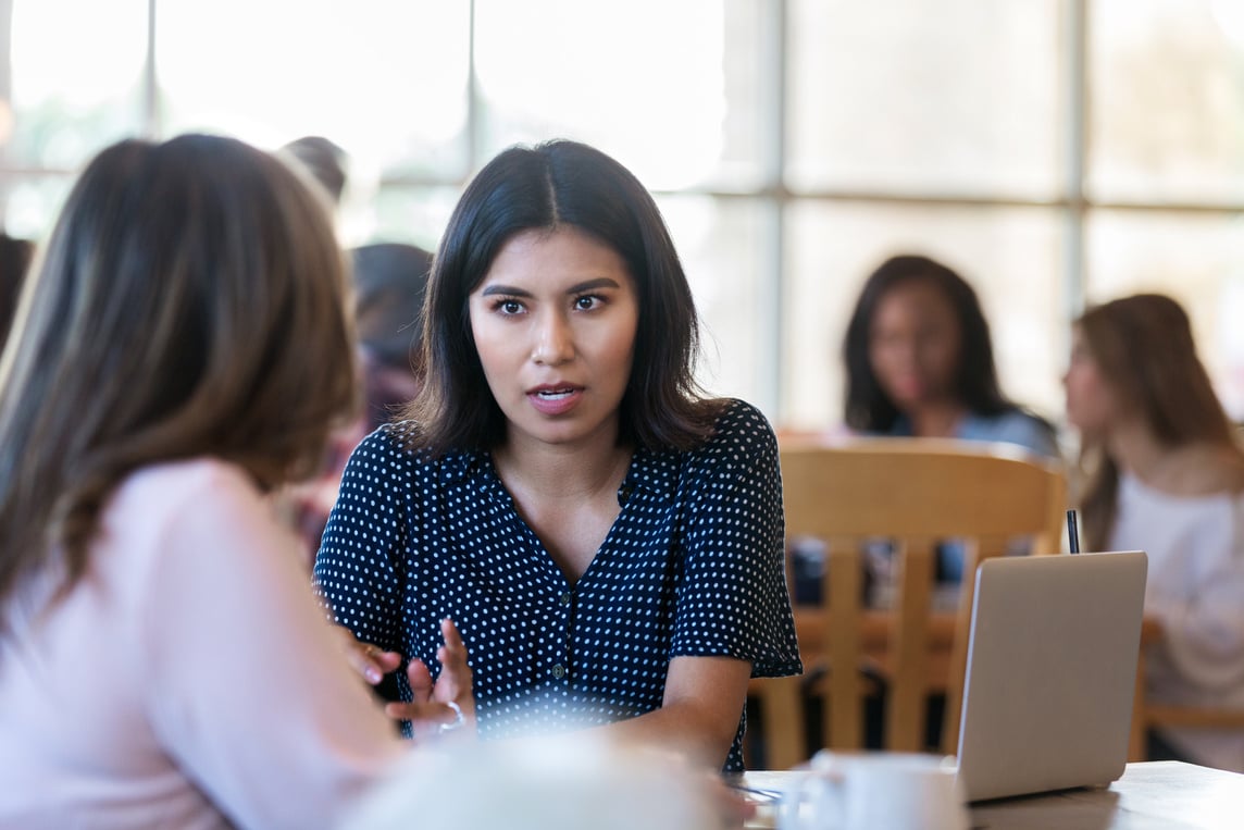 Two women have serious conversation at coffee shop.